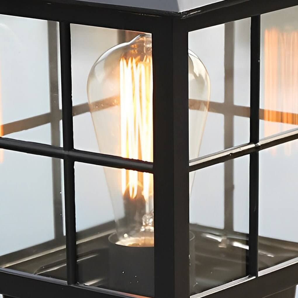 Stone light pillar with a black lantern, providing elegant lighting near a garden pathway.