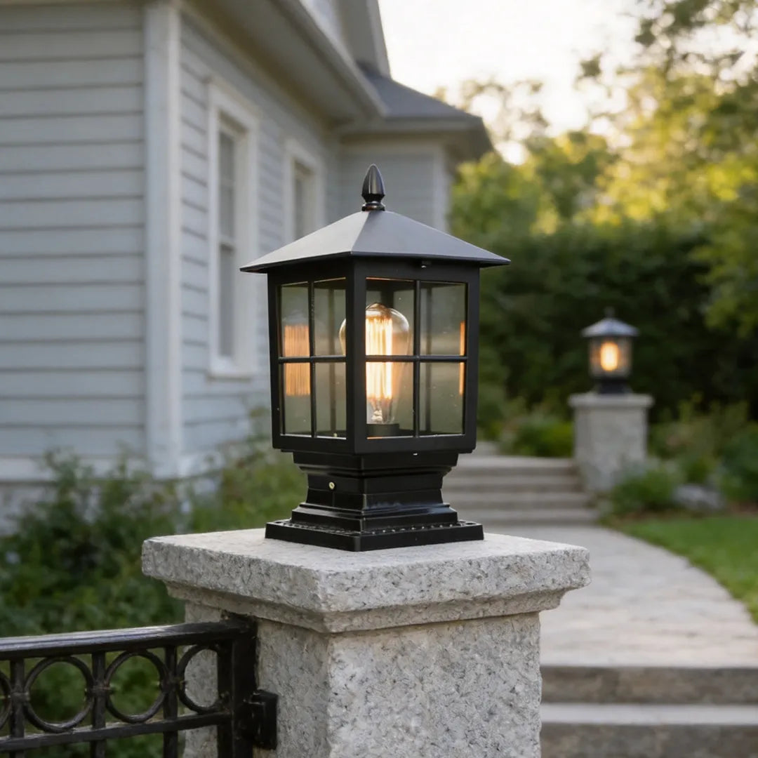 Stone light pillar mounted on a granite column beside a garden path, featuring a black lantern-style fixture.