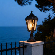 Black post light beside a stone pillar, elegant and functional outdoor lighting fixture