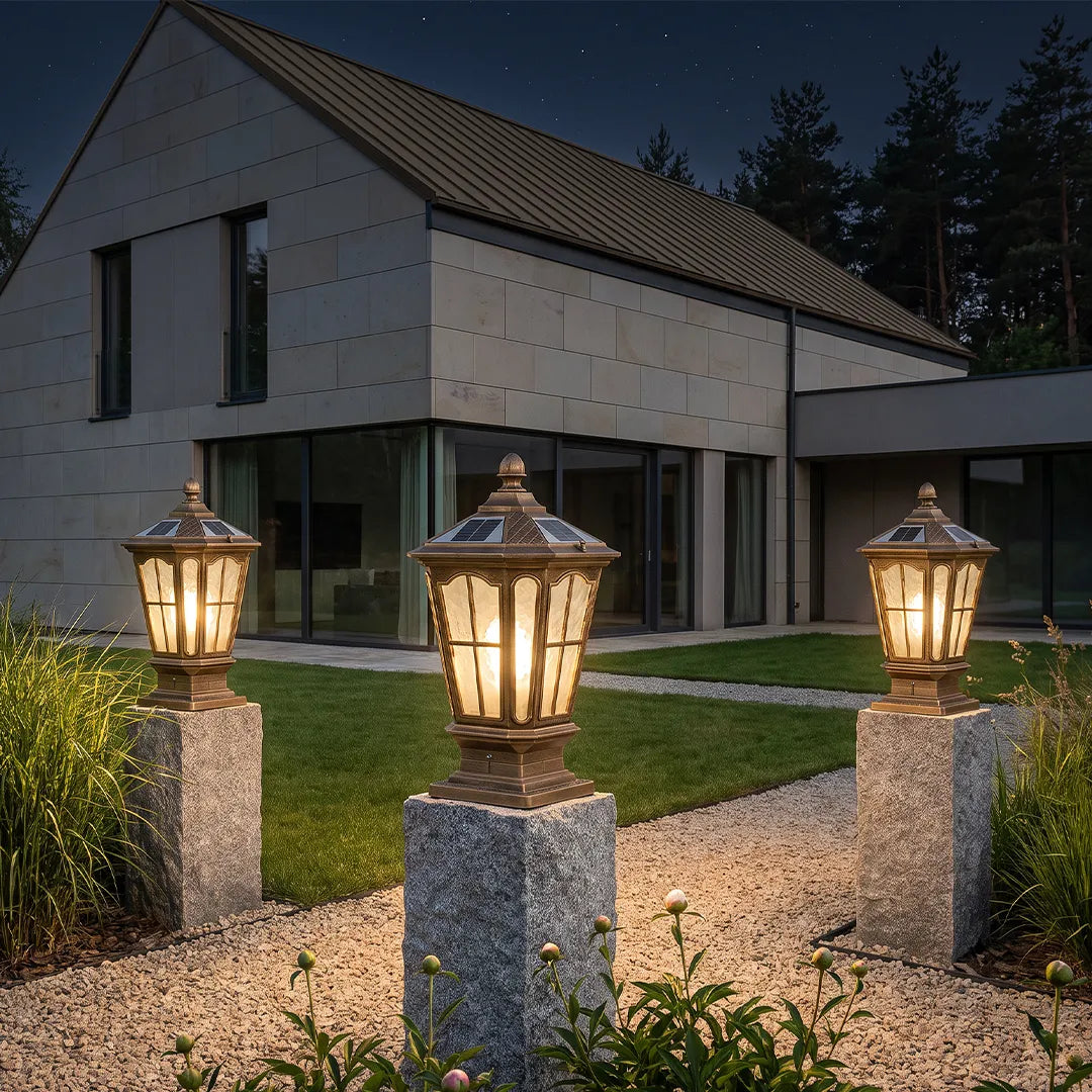 Stone pillar light fixtures installed on tall granite posts along a modern driveway with warm outdoor lighting.
