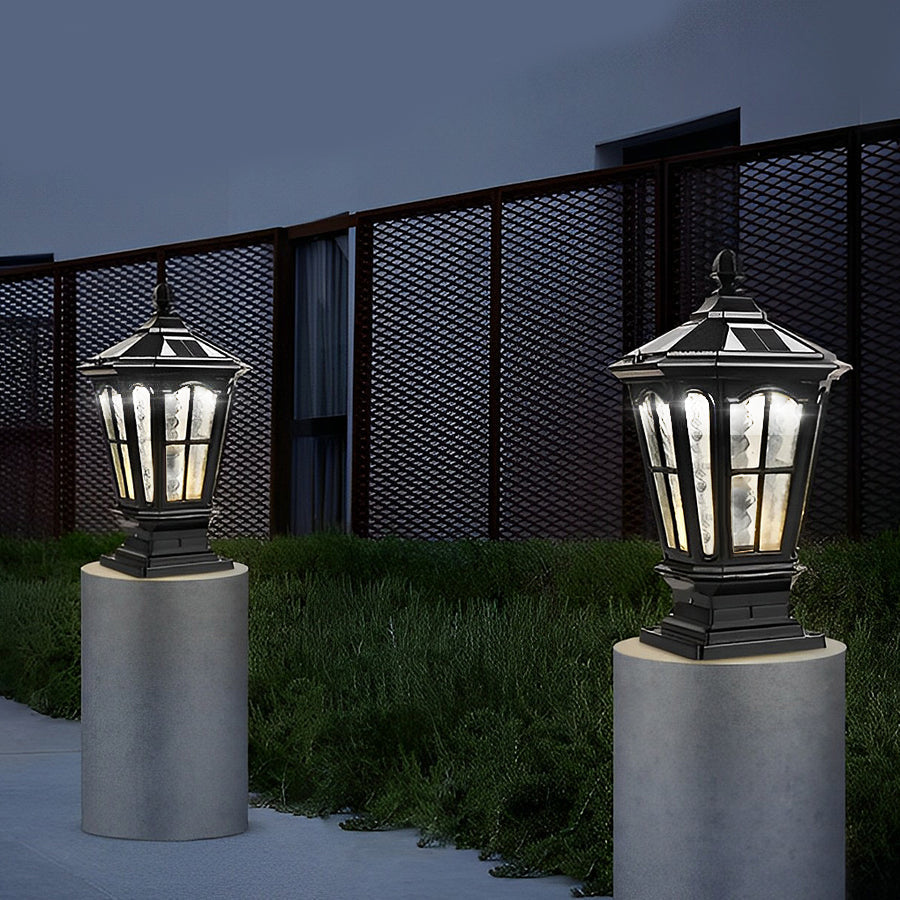 Modern black stone pillar light fixture with clear glass panels placed on concrete posts along outdoor pathway.