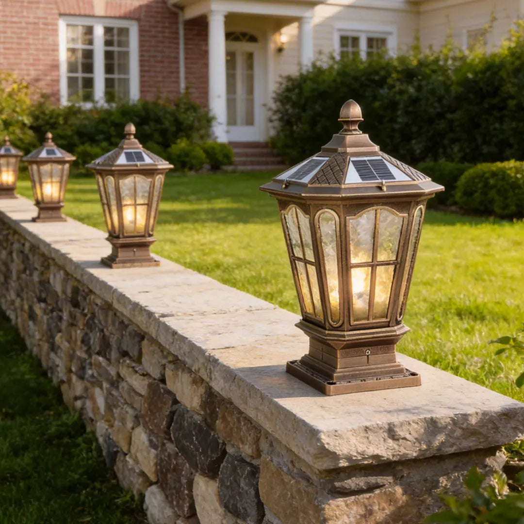 Stone pillar light fixtures arranged along a low stone wall in a front yard landscape.