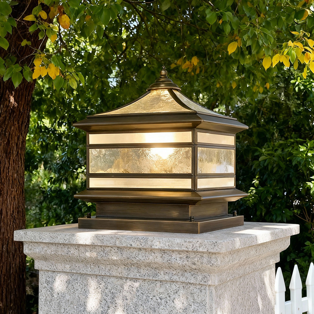 Classic stone pillar solar light placed on a concrete post surrounded by greenery.