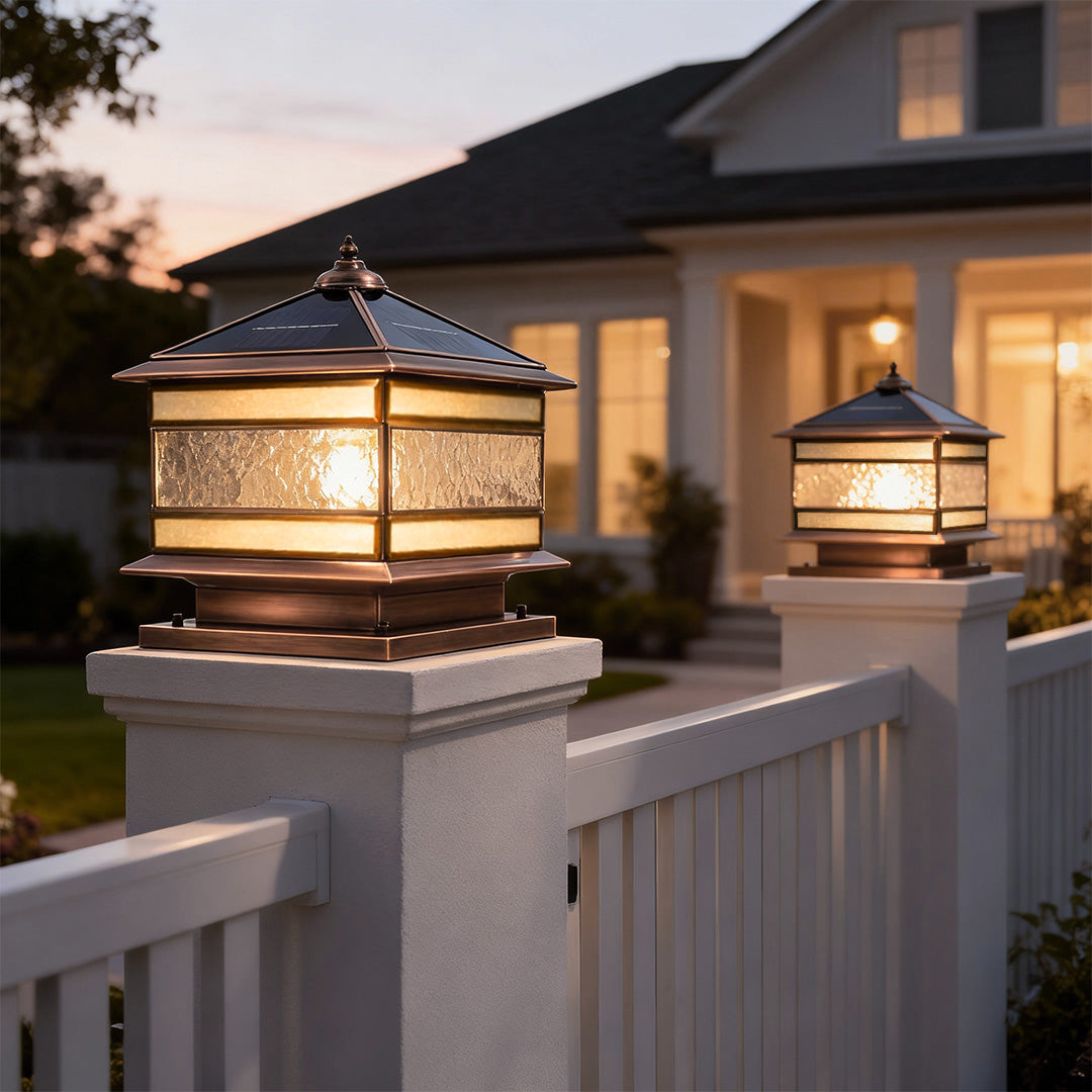 Solar powered stone pillar lights installed along a fence for outdoor pathway lighting.