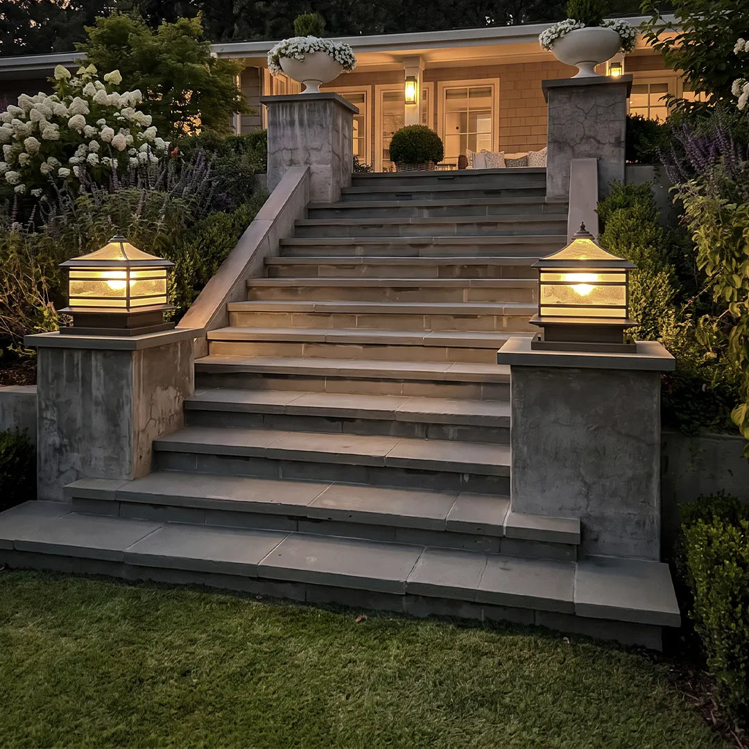 Stone pillar solar lights mounted on stair columns, illuminating a grand outdoor staircase at dusk.
