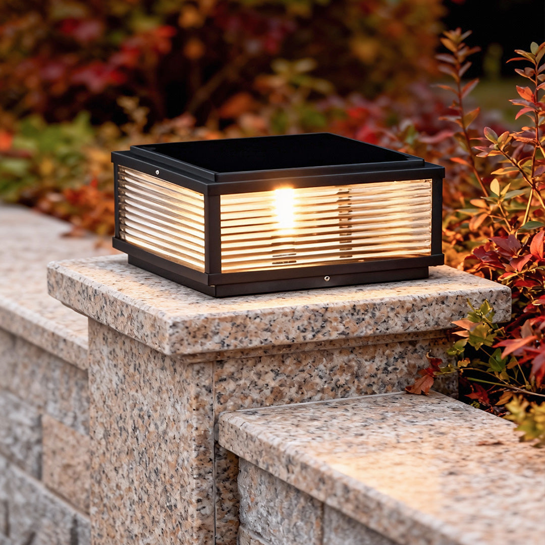 Square pillar light installed on stone pillar beside colorful shrubs, providing stylish garden illumination