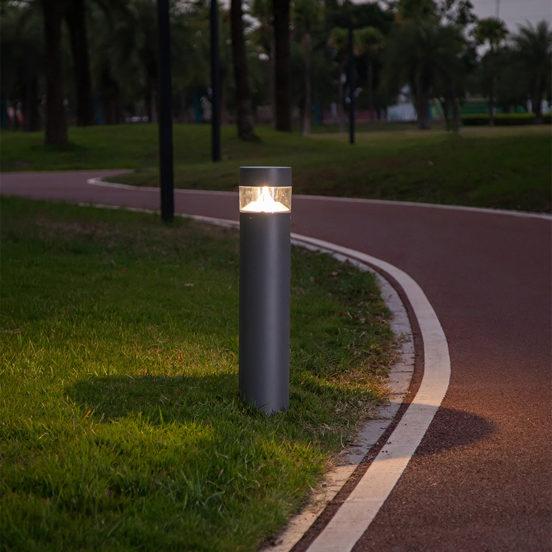 Modern bollard light creating ambient illumination against textured stone wall backdrop