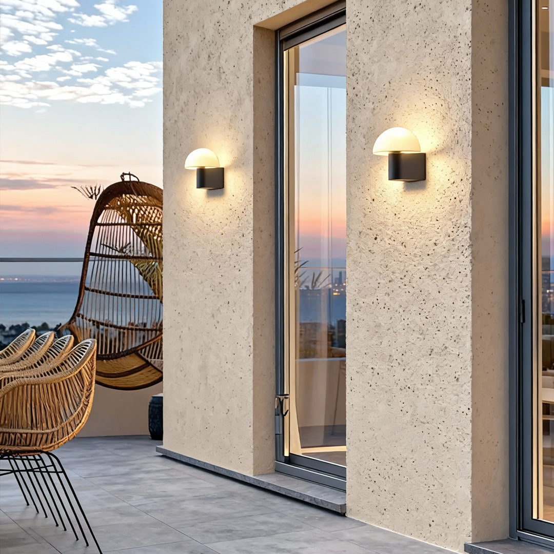 Modern outdoor wall light sconce placed beside a textured stone wall, illuminating a contemporary home entrance.