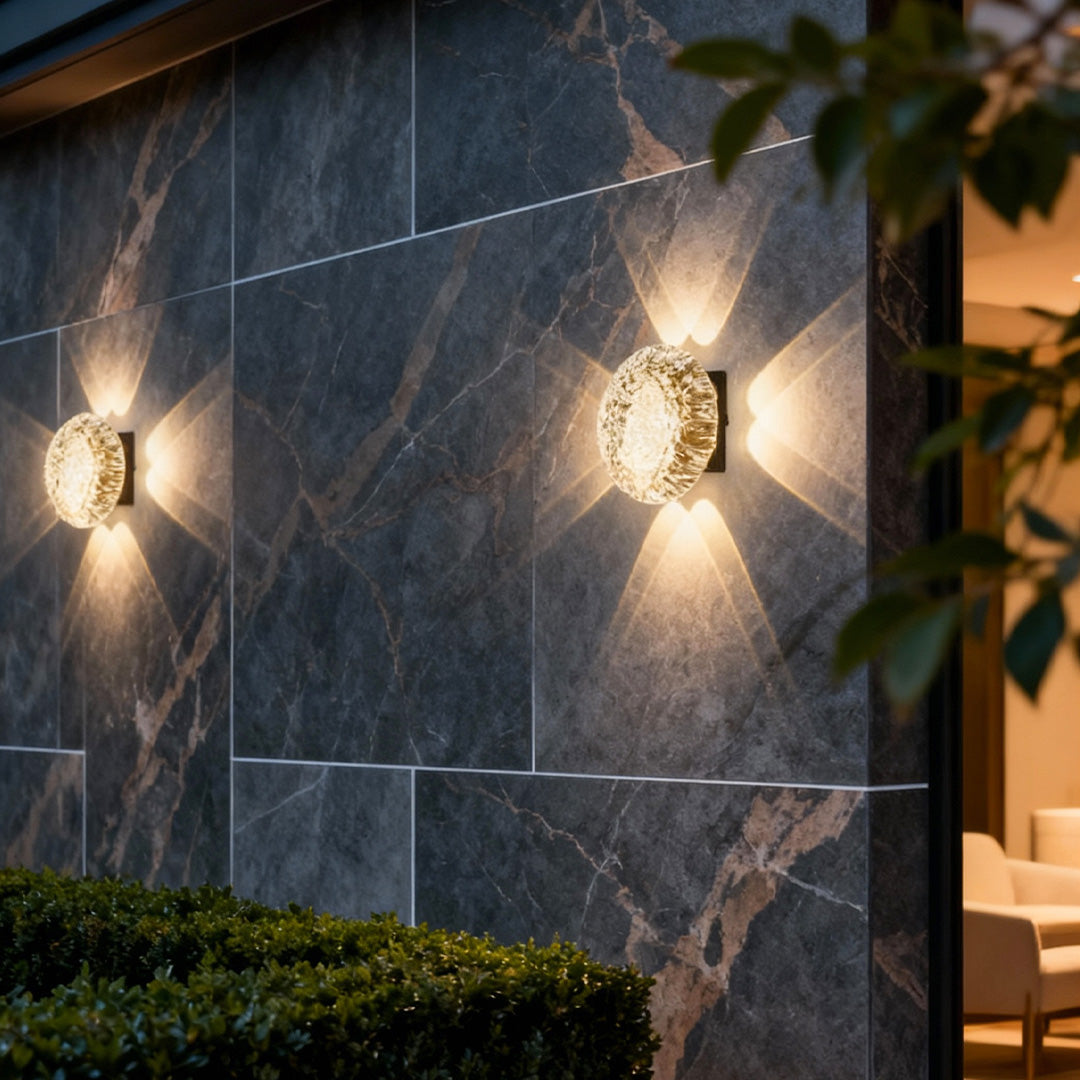 Modern gold up and down outdoor wall lights illuminating a dark stone exterior wall with symmetrical vertical light beams.