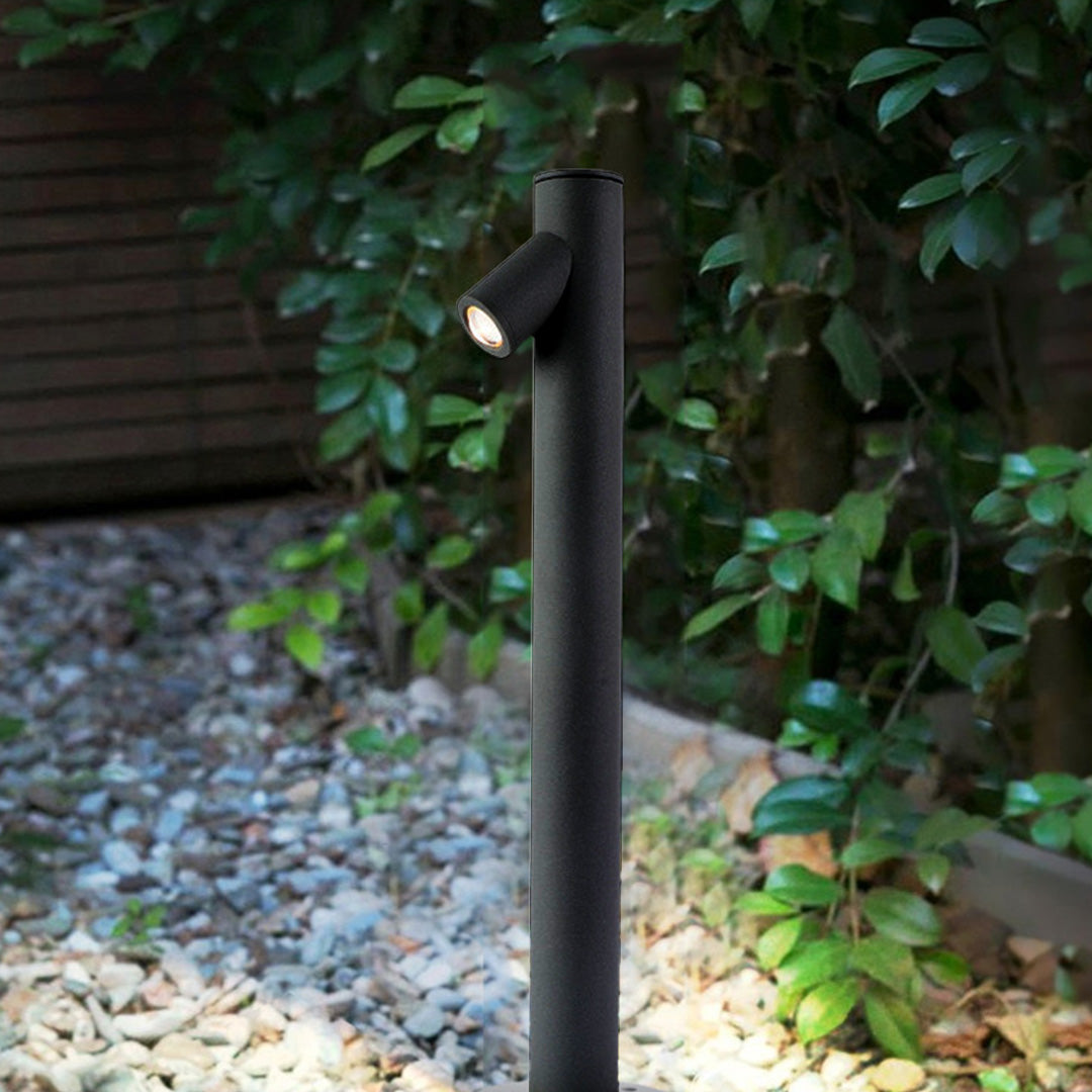 LED path light illuminating natural stone retaining wall with moss and lawn in residential landscape