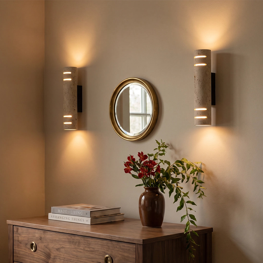Stone wall light mounted above a wood console table, casting warm up and down light in a cozy interior.