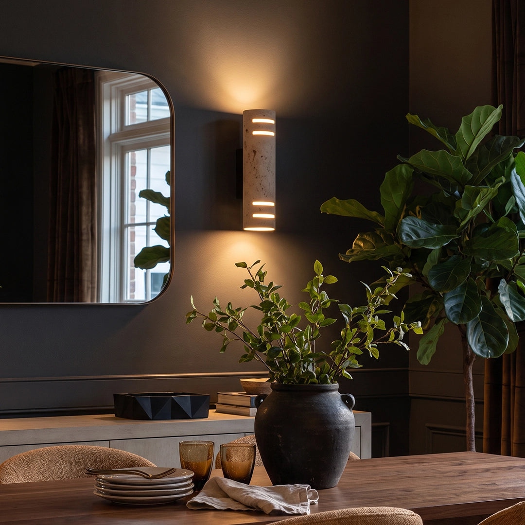 Stone wall light mounted on a dark wall near a window, adding soft upward and downward glow to a moody interior.