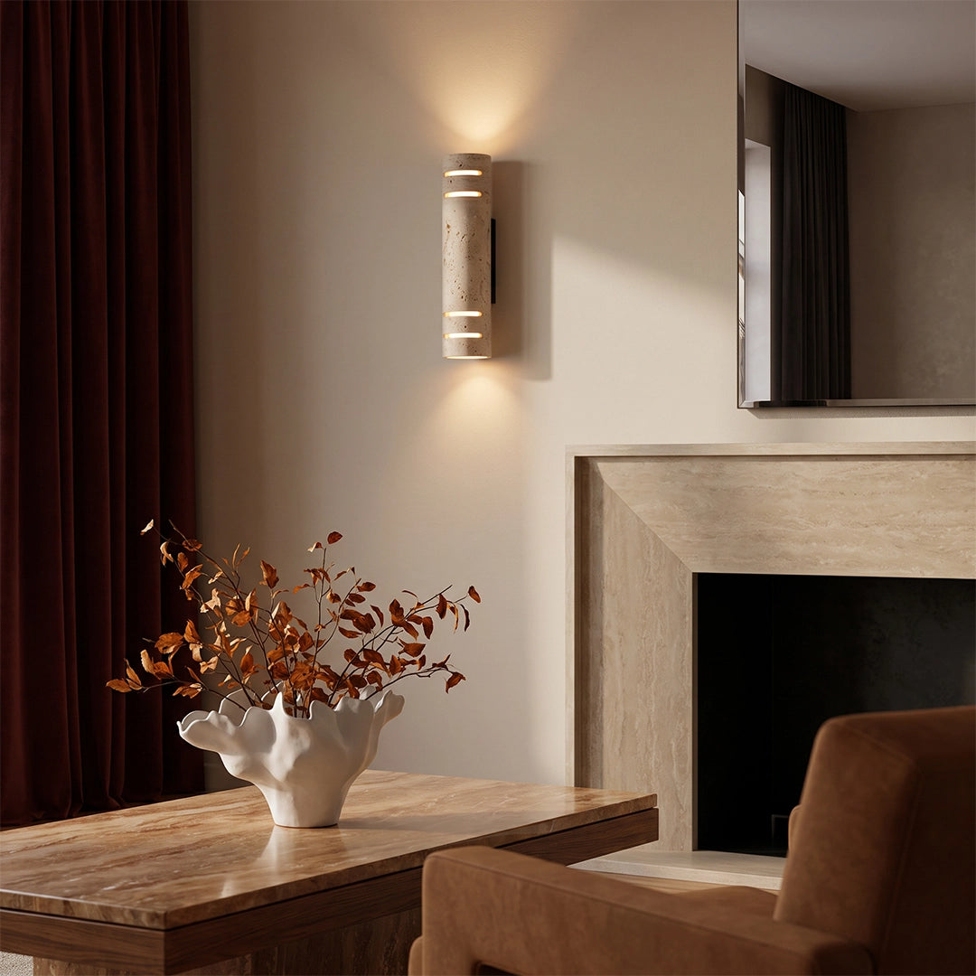 Stone wall light fixed on a wall beside a fireplace, creating soft up and down illumination in a refined interior.
