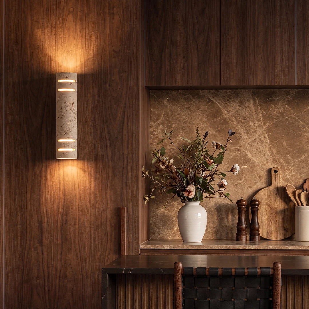 Stone wall light mounted on a dark wood accent wall, bringing warm decorative lighting to a modern dining space.