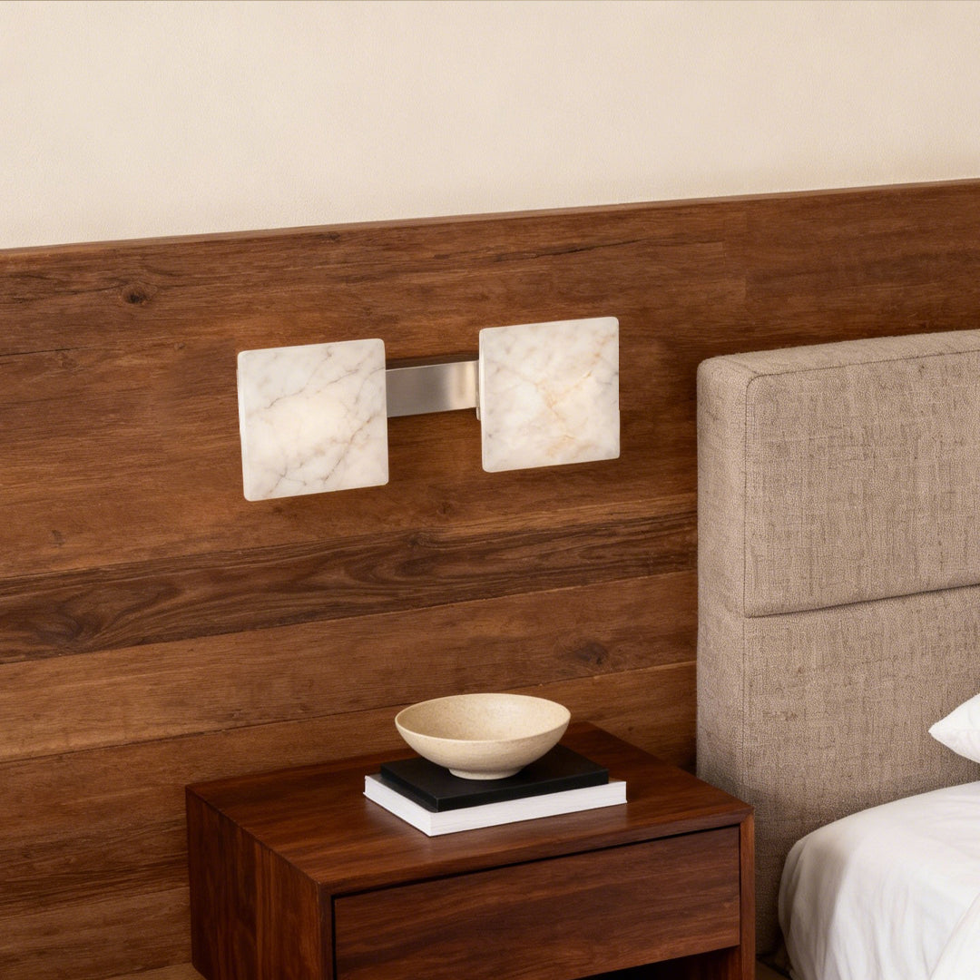 Dual stone wall sconce lighting illuminating wooden headboard wall in contemporary bedroom with natural materials