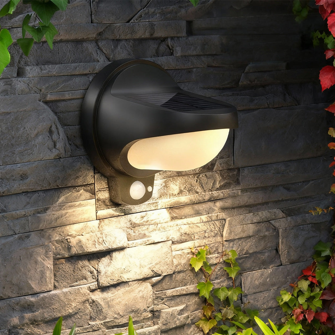 Vintage outdoor wall lights illuminating a stone garden wall at night.