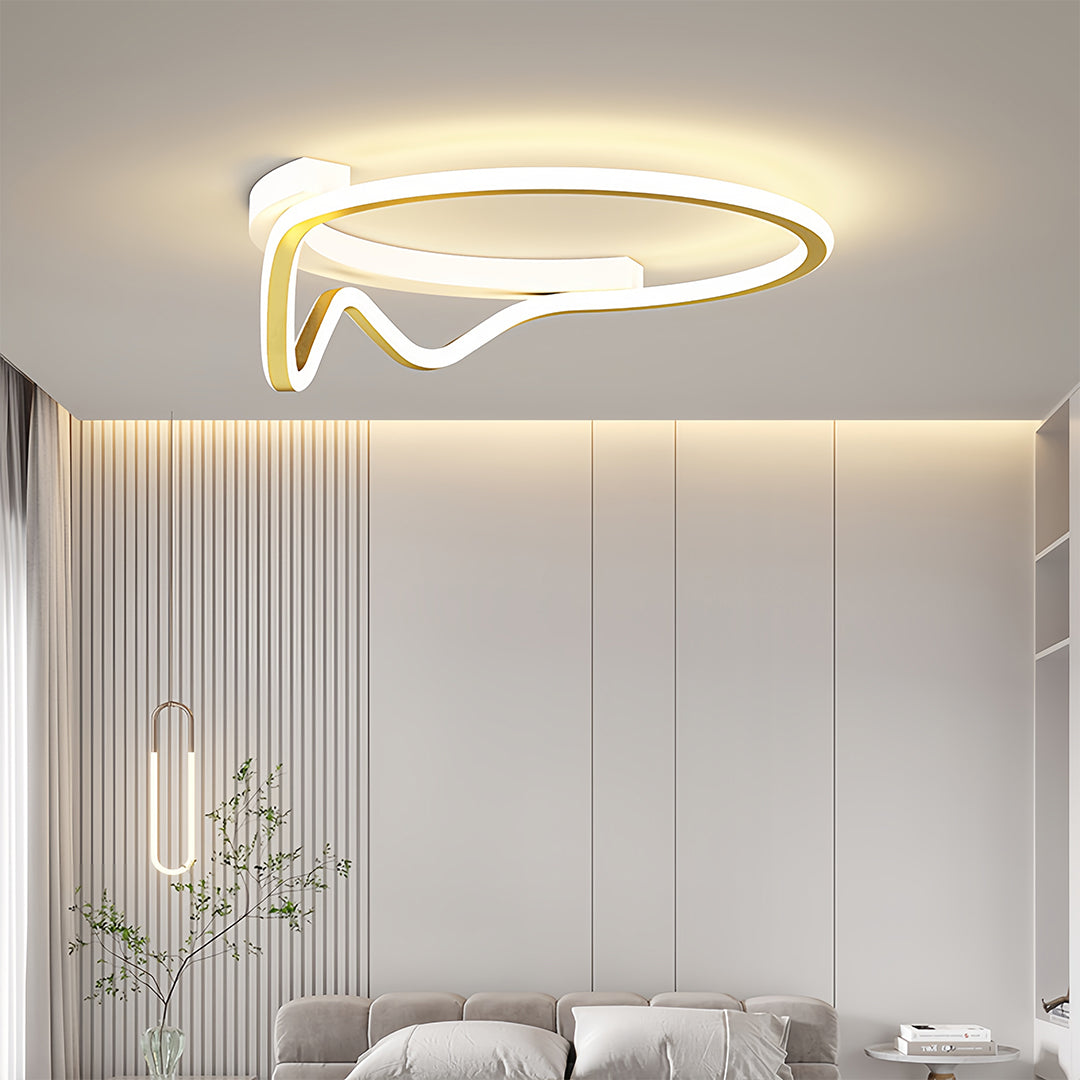 Streamlined gold geometric flush mount light fixture providing soft overhead illumination in a contemporary bedroom setting.