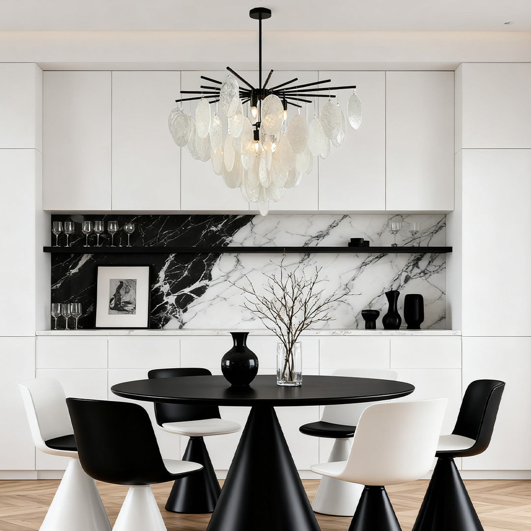 Stunning mother of pearl chandelier with a black spoke frame, suspended above a modern dining table in a high-contrast black and white kitchen.
