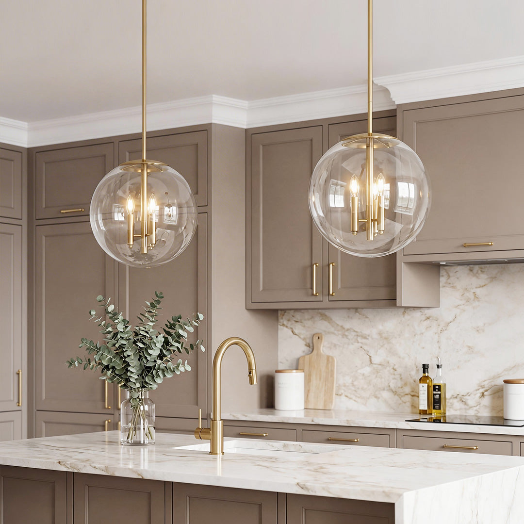 Stunning clear globe pendant light with a gold candelabra base in a luxury marble kitchen.