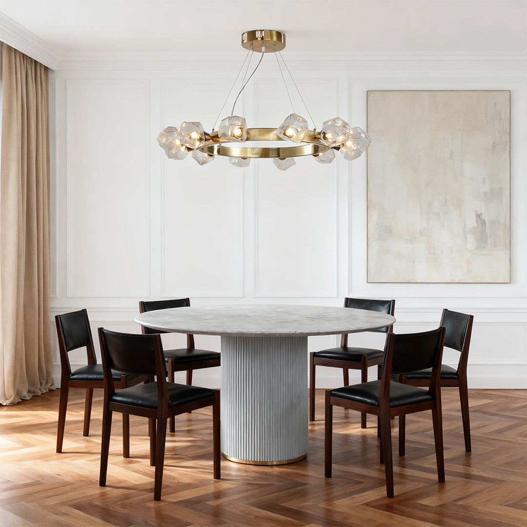 Sleek modern dining room with a stunning gold round chandelier featuring crystal accents over a gray marble rectangular table.