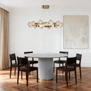 Sleek modern dining room with a stunning gold round chandelier featuring crystal accents over a gray marble rectangular table.