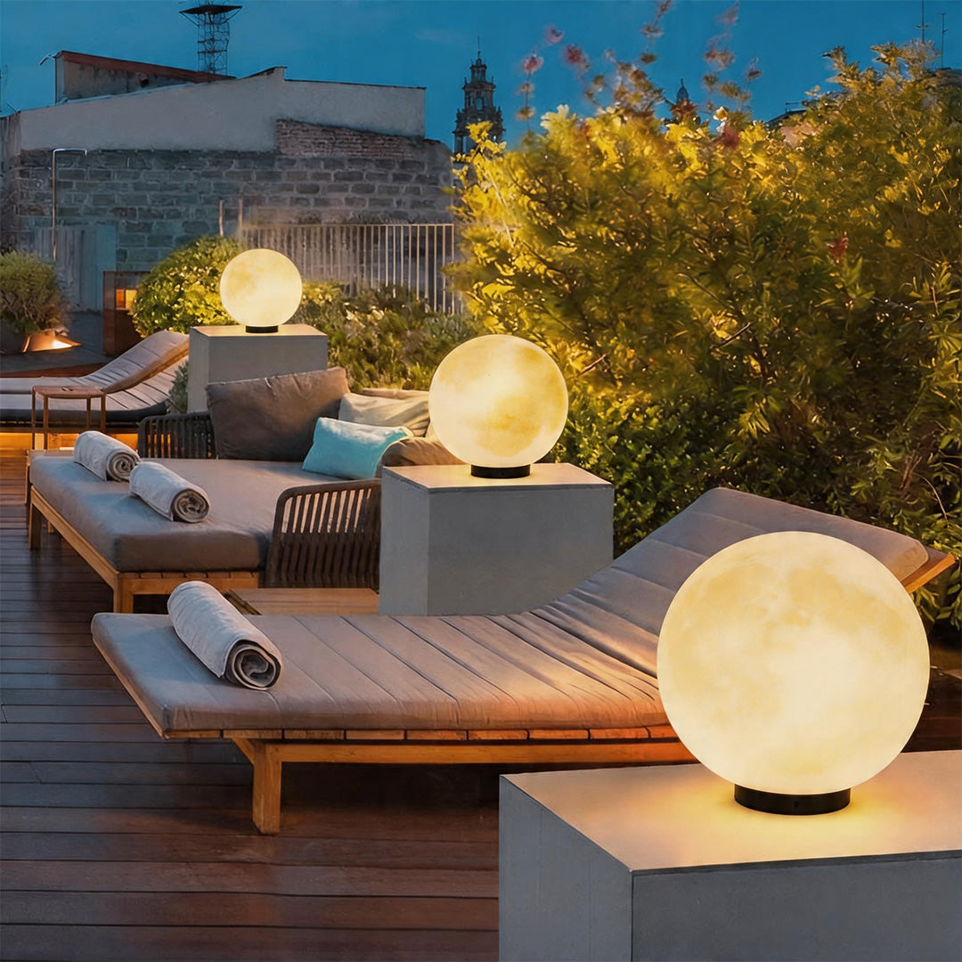 Stunning moon pillar lights glowing on a modern rooftop terrace near elegant lounge chairs.