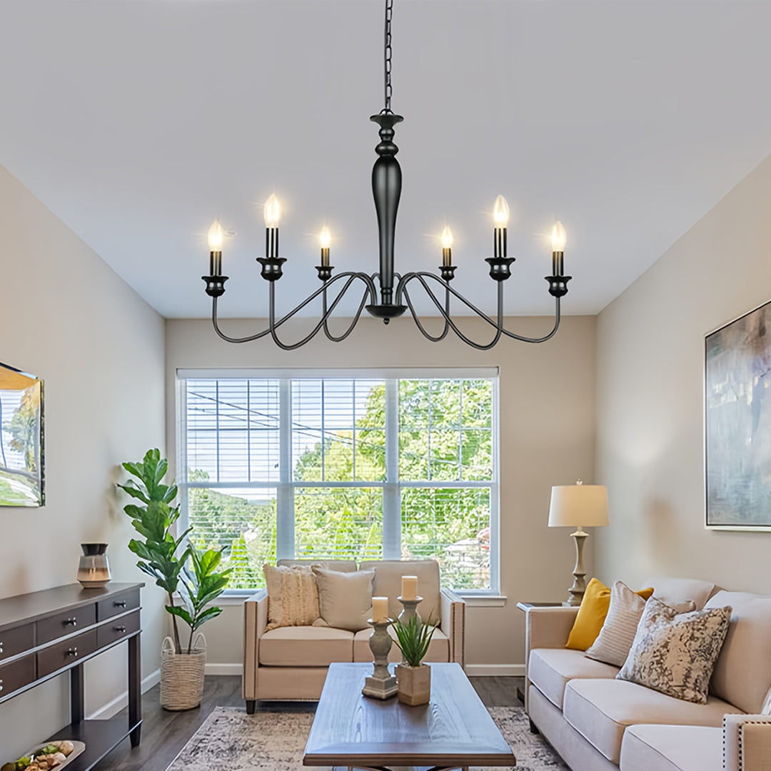 Stylish black candle chandelier illuminating bright dining room with white chairs and natural light