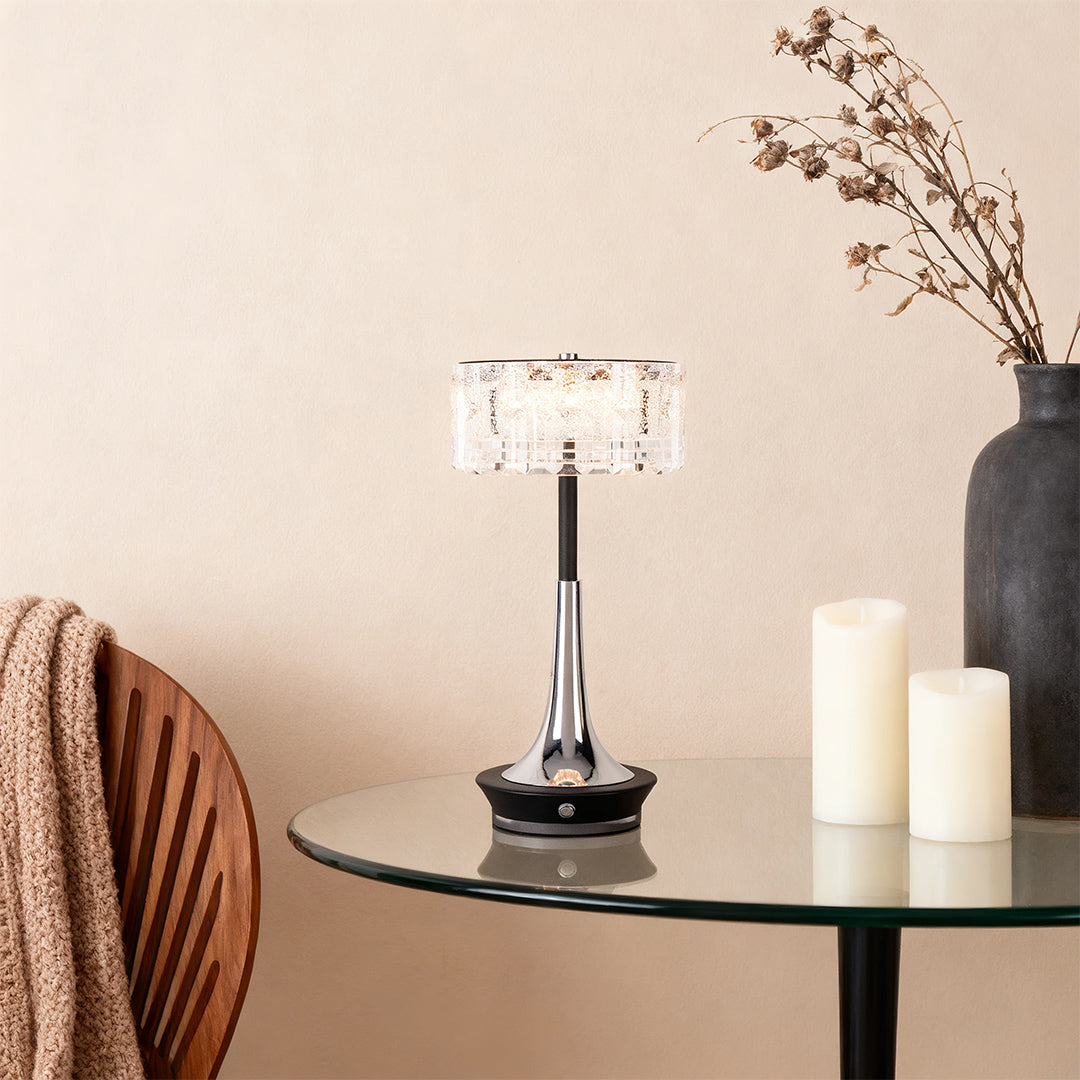 A stylish black and chrome cordless mushroom table lamp providing soft accent lighting on a glass side table. 