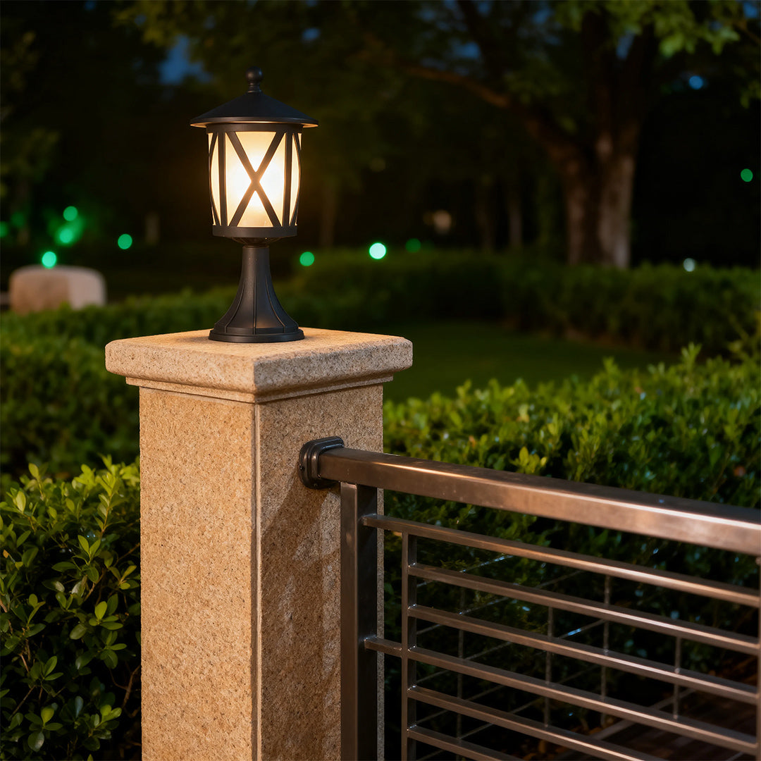 Stylish black outdoor pillar light casting amber glow on textured stone post in landscaped entrance