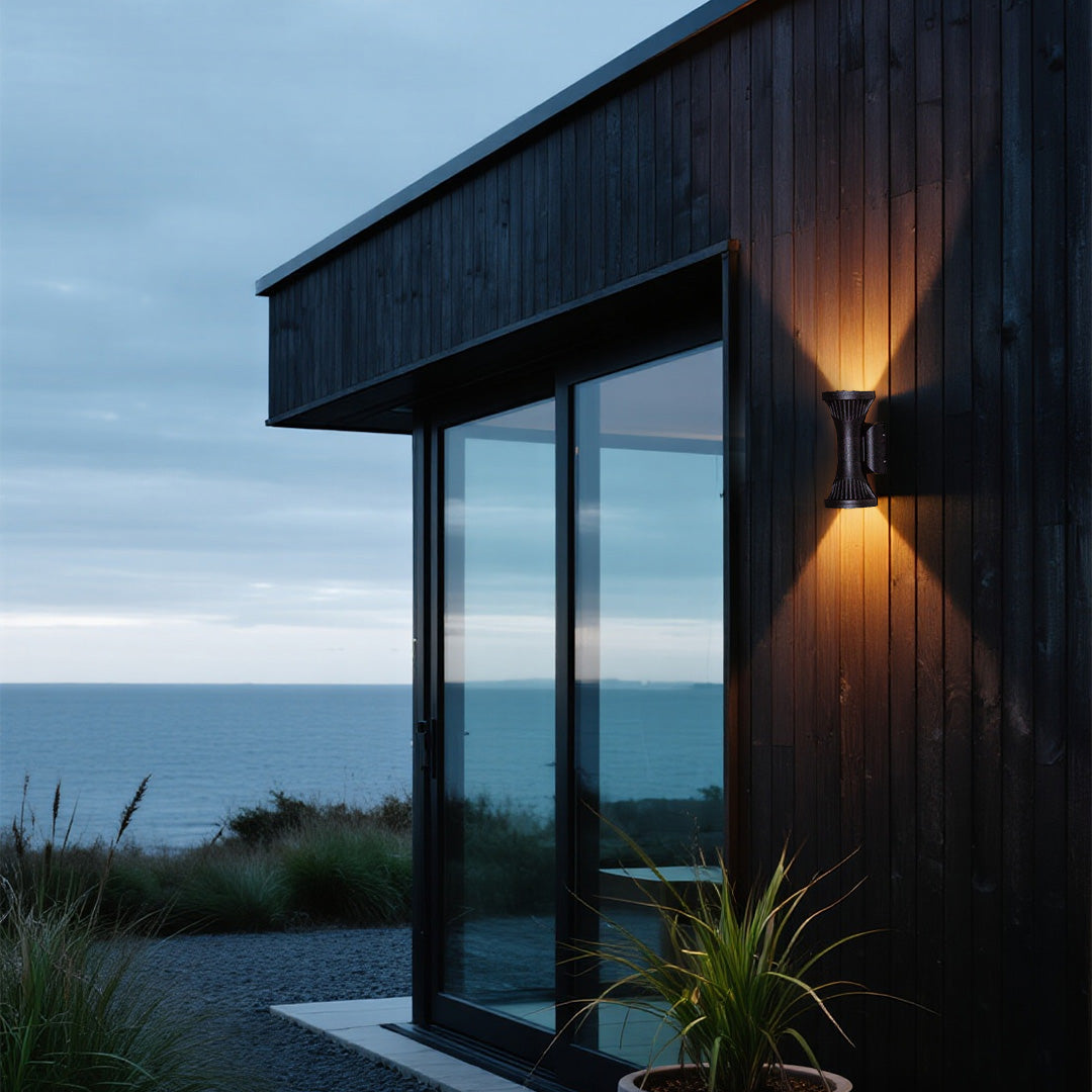 Coastal cabin exterior highlighted by a stylish black Outdoor Wall Lighting Fixture casting a focused light pattern at dusk.