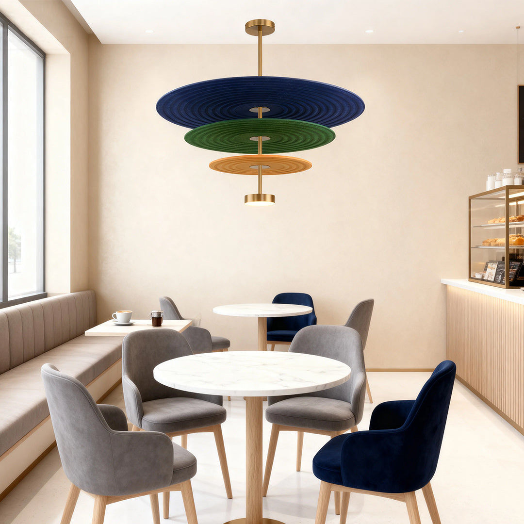 A stylish blue and green 3 tier chandelier illuminating a cozy cafe seating area with round tables and upholstered chairs.