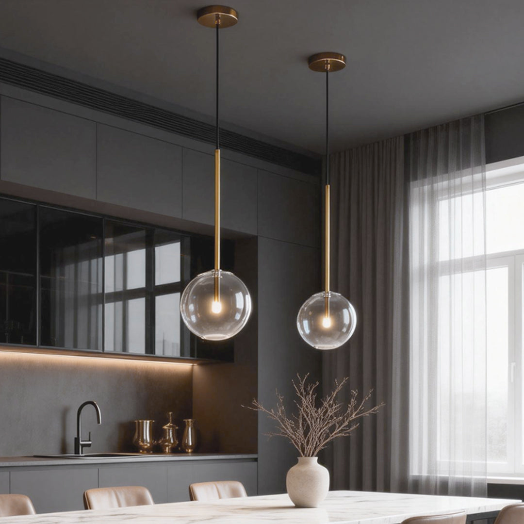 Stylish clear glass globe pendant light with a sleek golden stem, providing soft and ambient light in contemporary interiors.