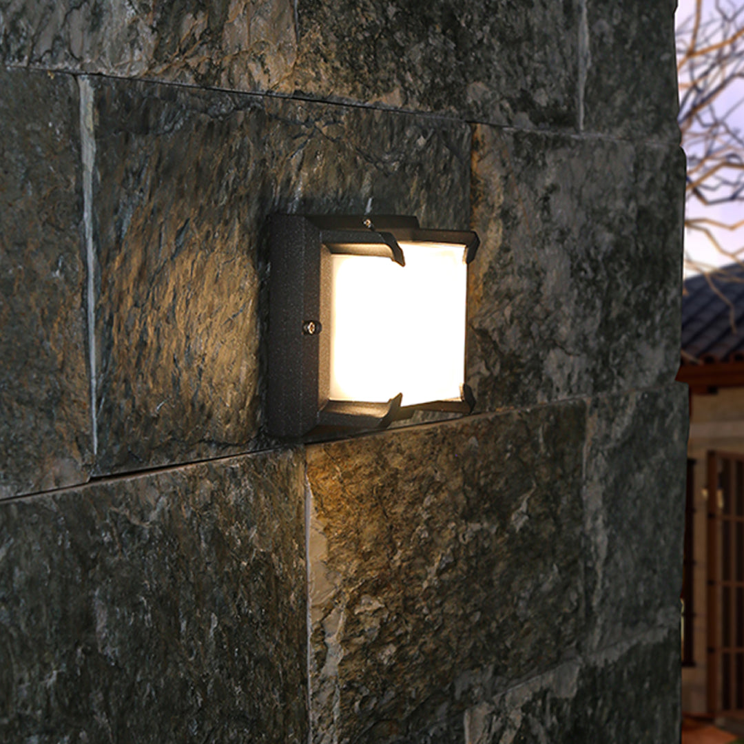 Stylish dark stone column accented by a cube-shaped Black Outdoor Wall Light casting a soft, warm glow.