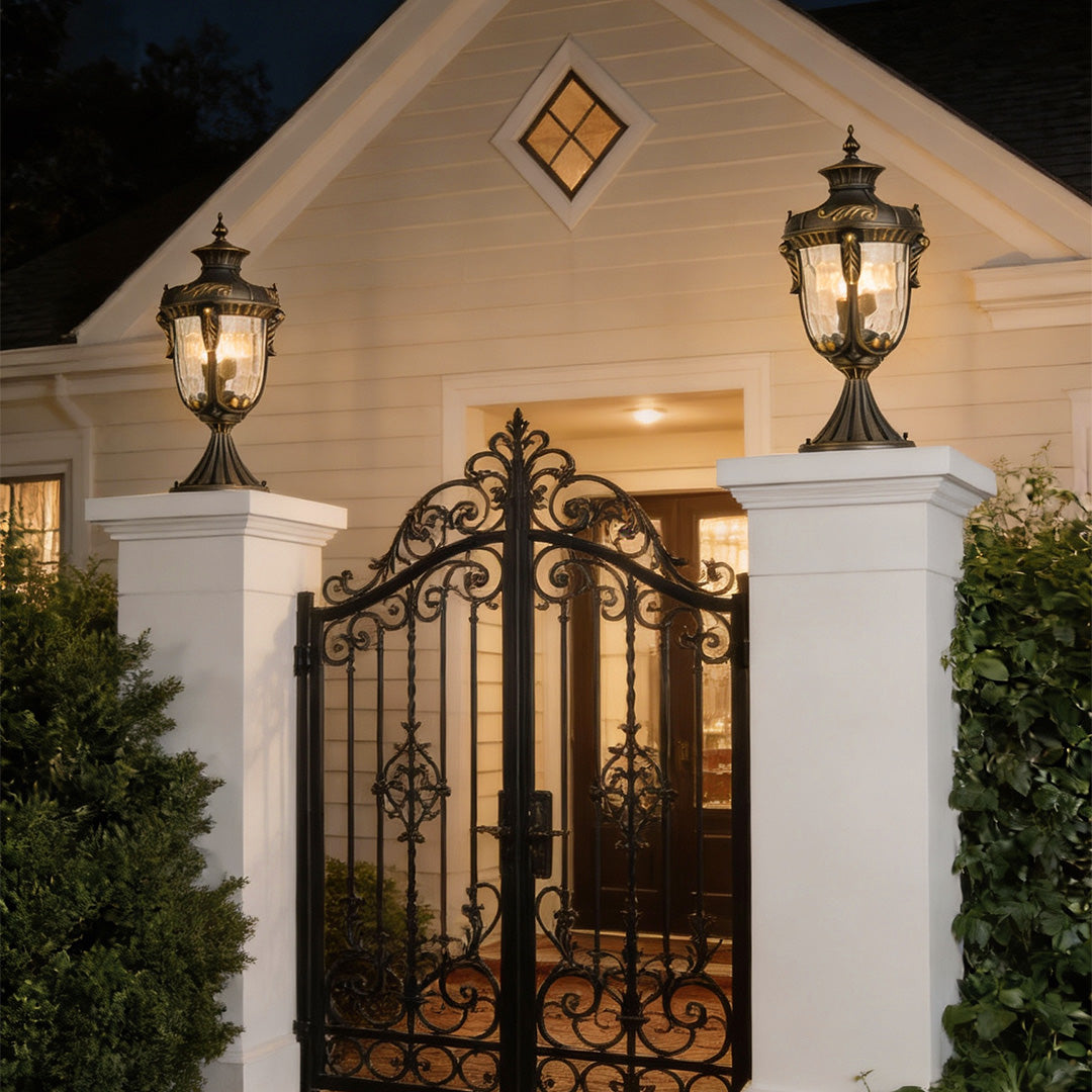 Stylish outdoor pillar lights for house providing soft illumination for a gated entrance at night.