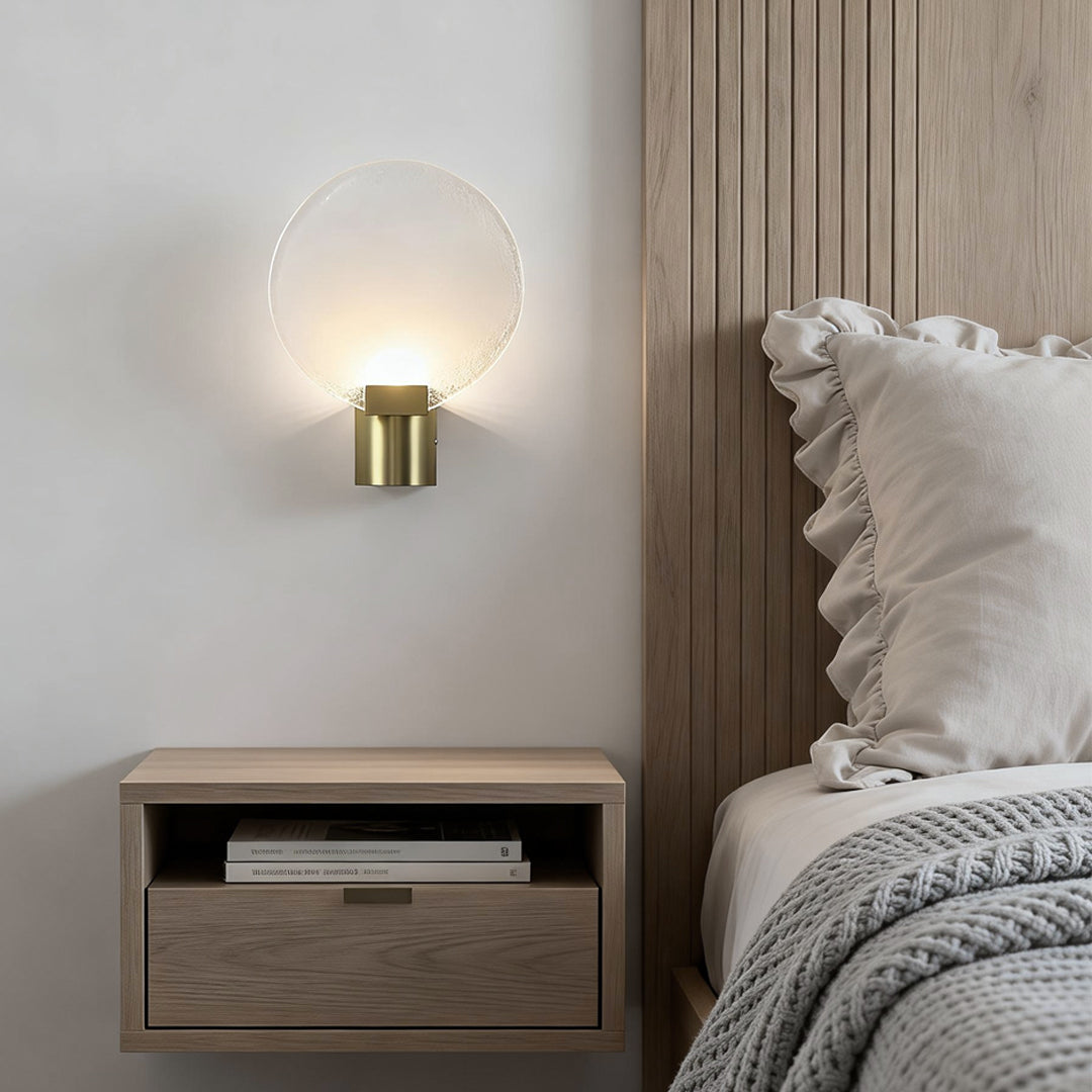 Stylish round wall light with a frosted glass shade, installed near a bed with soft lighting for a relaxing ambiance.