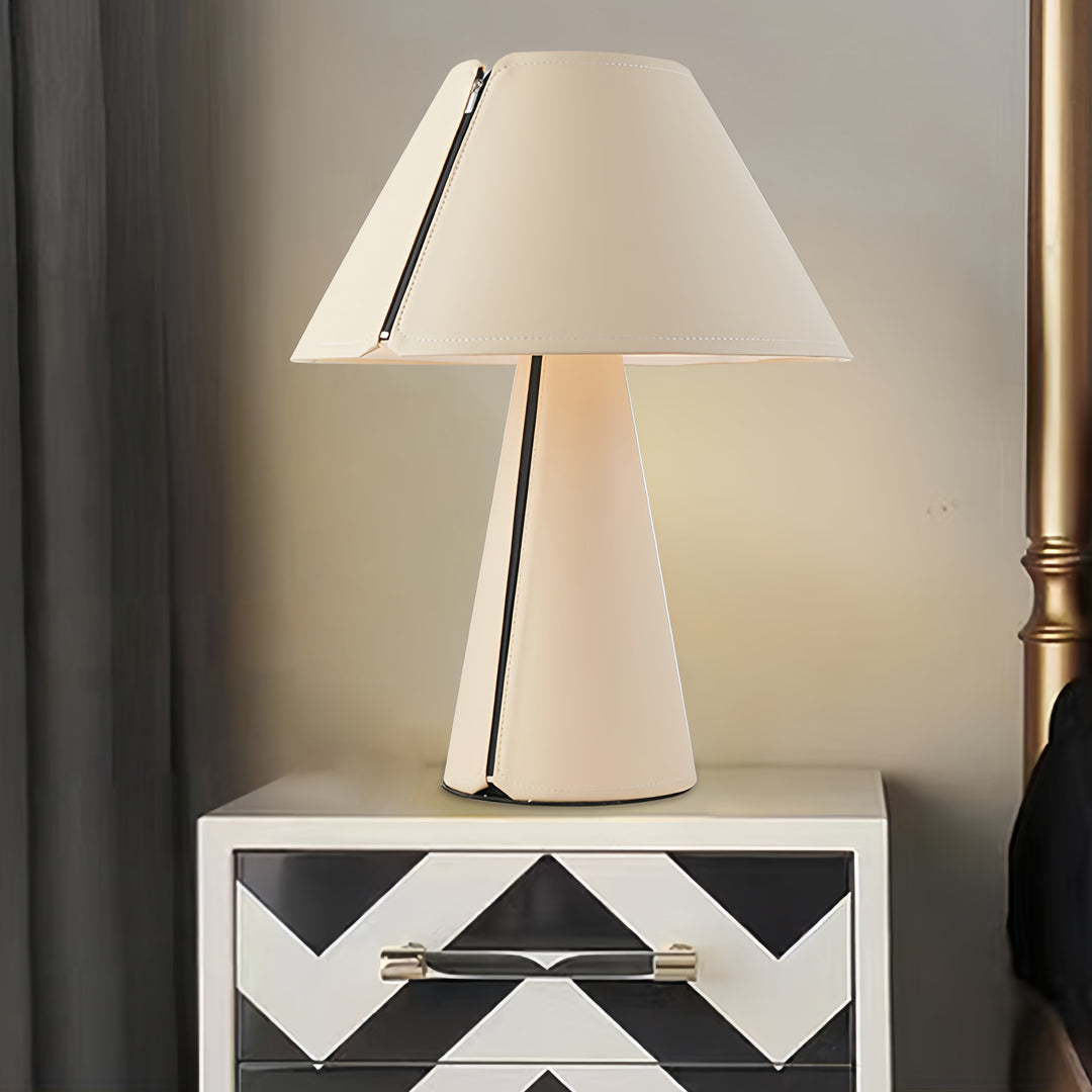 Stylish white table lamp illuminating bedroom nightstand with soft warm light