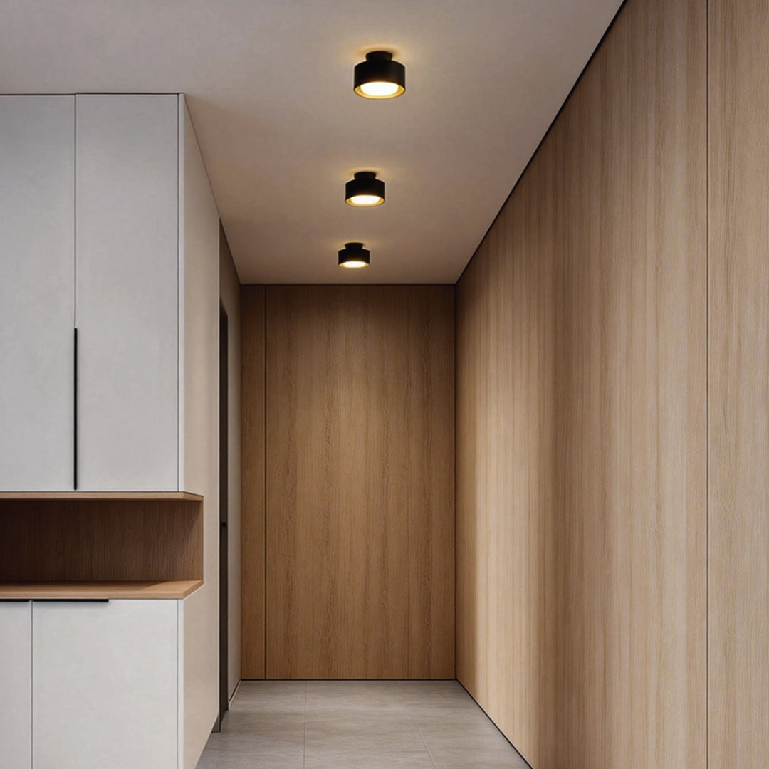Surface mounted LED downlight providing soft light in a hallway with wooden paneling.