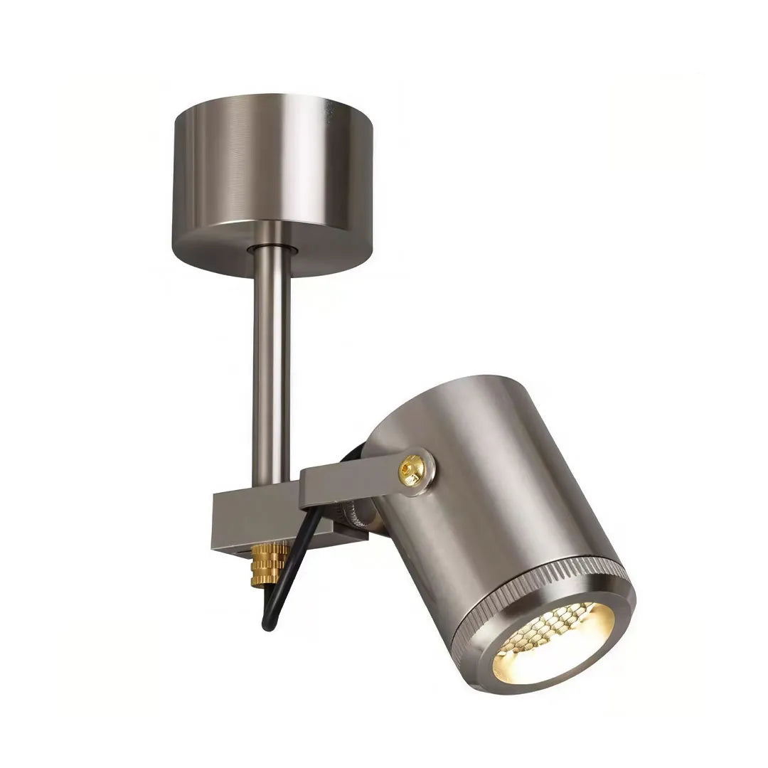 Spotlight ceiling light with an adjustable cylindrical head and round surface-mounted ceiling canopy.