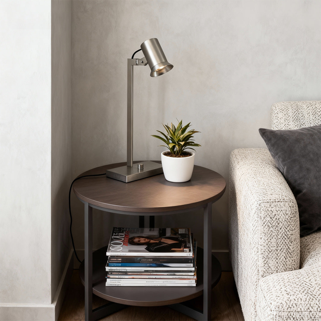Stylish swing arm desk lamps on round wooden side table beside cozy chair.