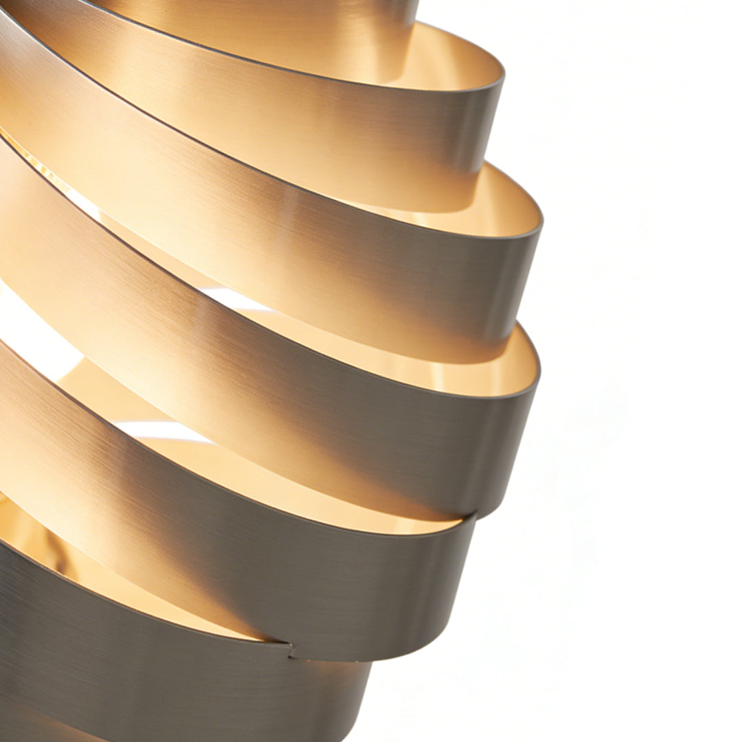 Close up view of a swirl pendant light showing layered curved metal bands with warm illumination and sculptural modern design.