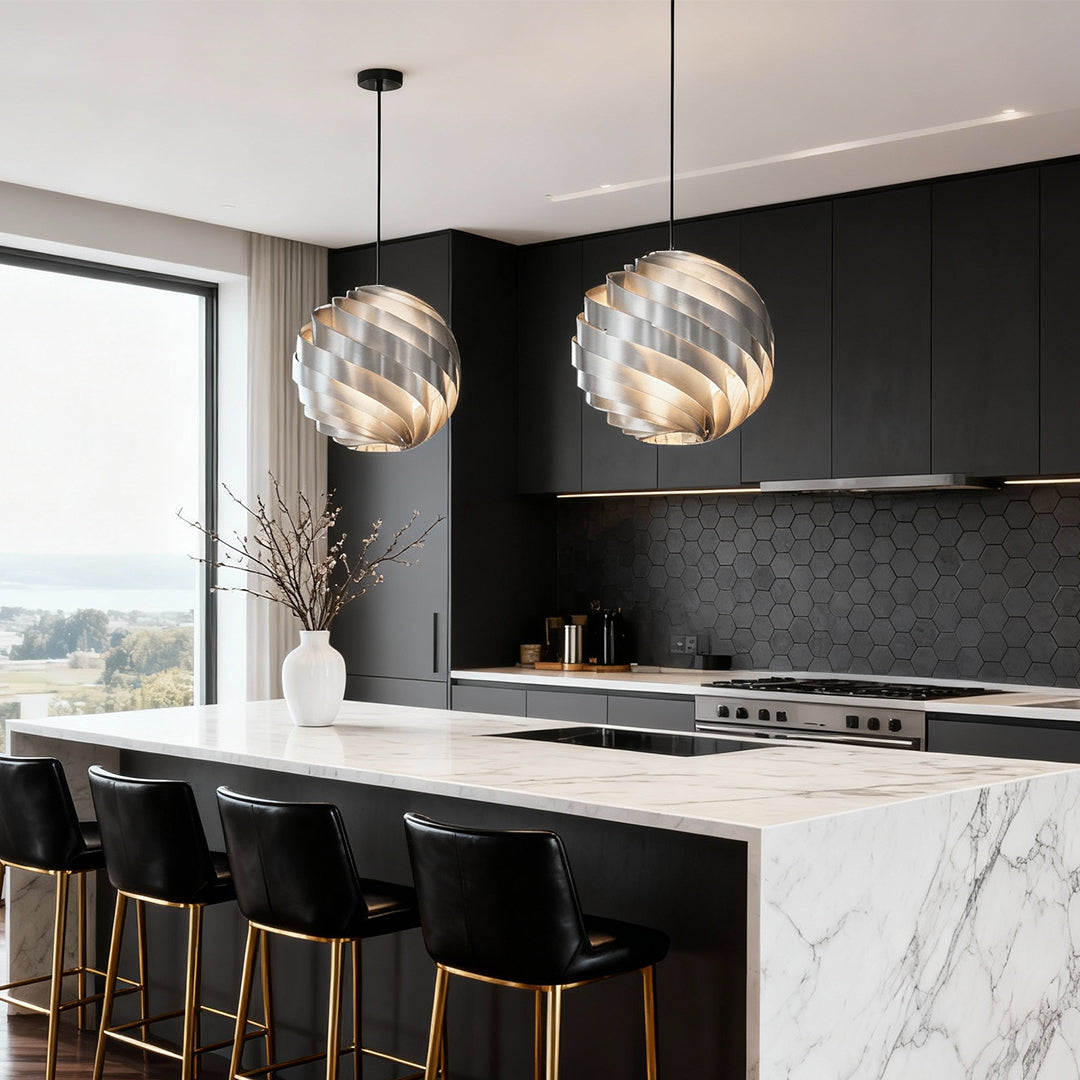 Pair of swirl pendant lights hanging above kitchen island with marble countertop.