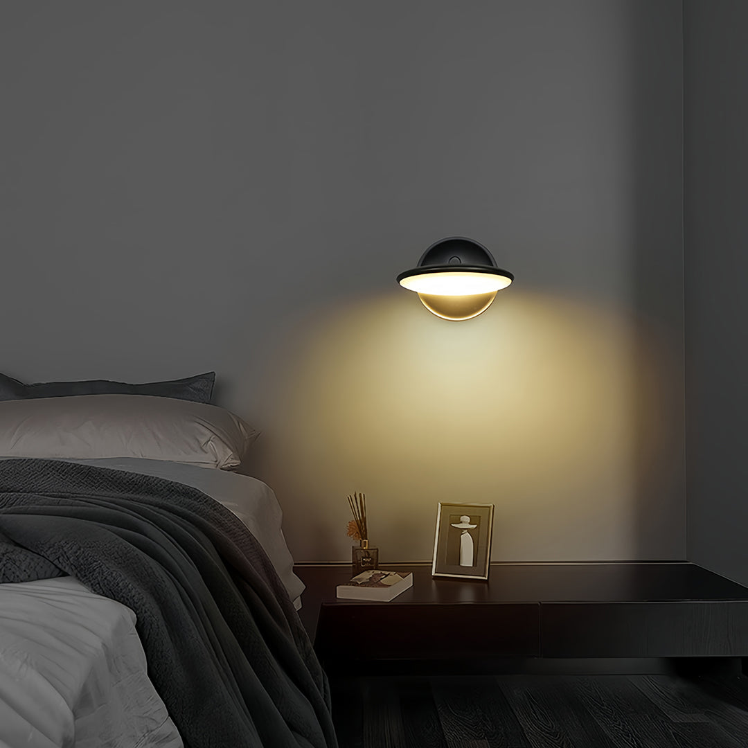 Swivel wall light providing bedside illumination in moody bedroom with dark bedding and minimal decor