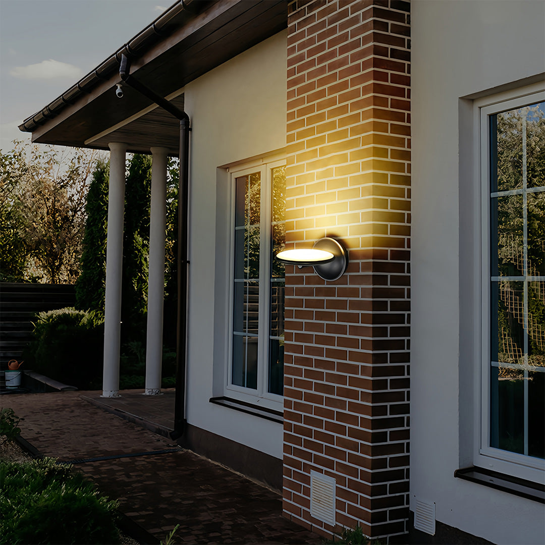 Swivel wall light mounted beside brick home entrance with covered patio and glass doors