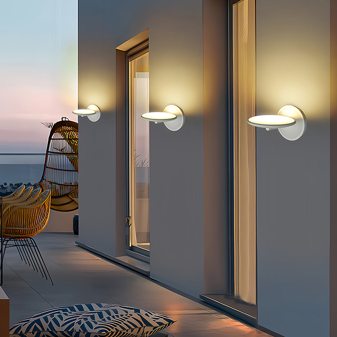 Swivel wall lights installed on outdoor corridor with decorative pebbles and wooden siding at sunset