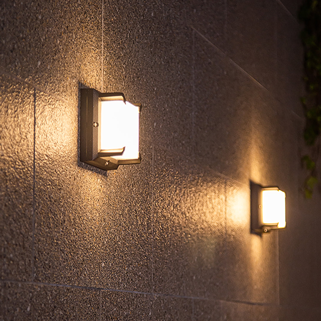 Symmetrical pair of rectangular Black Outdoor Wall Light fixtures providing ambient lighting on a dark textured facade.
