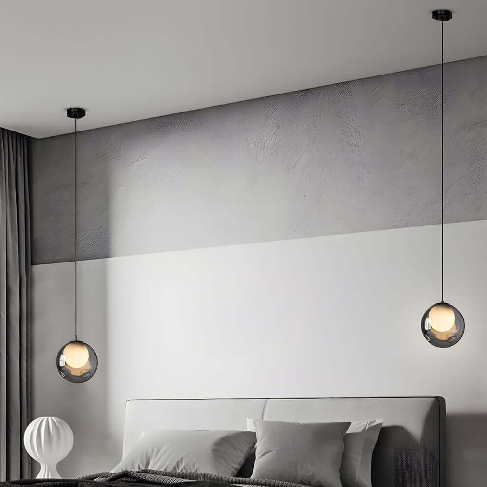 Symmetrical pair of smoked glass pendant lights used as bedside hanging lamps in a modern house