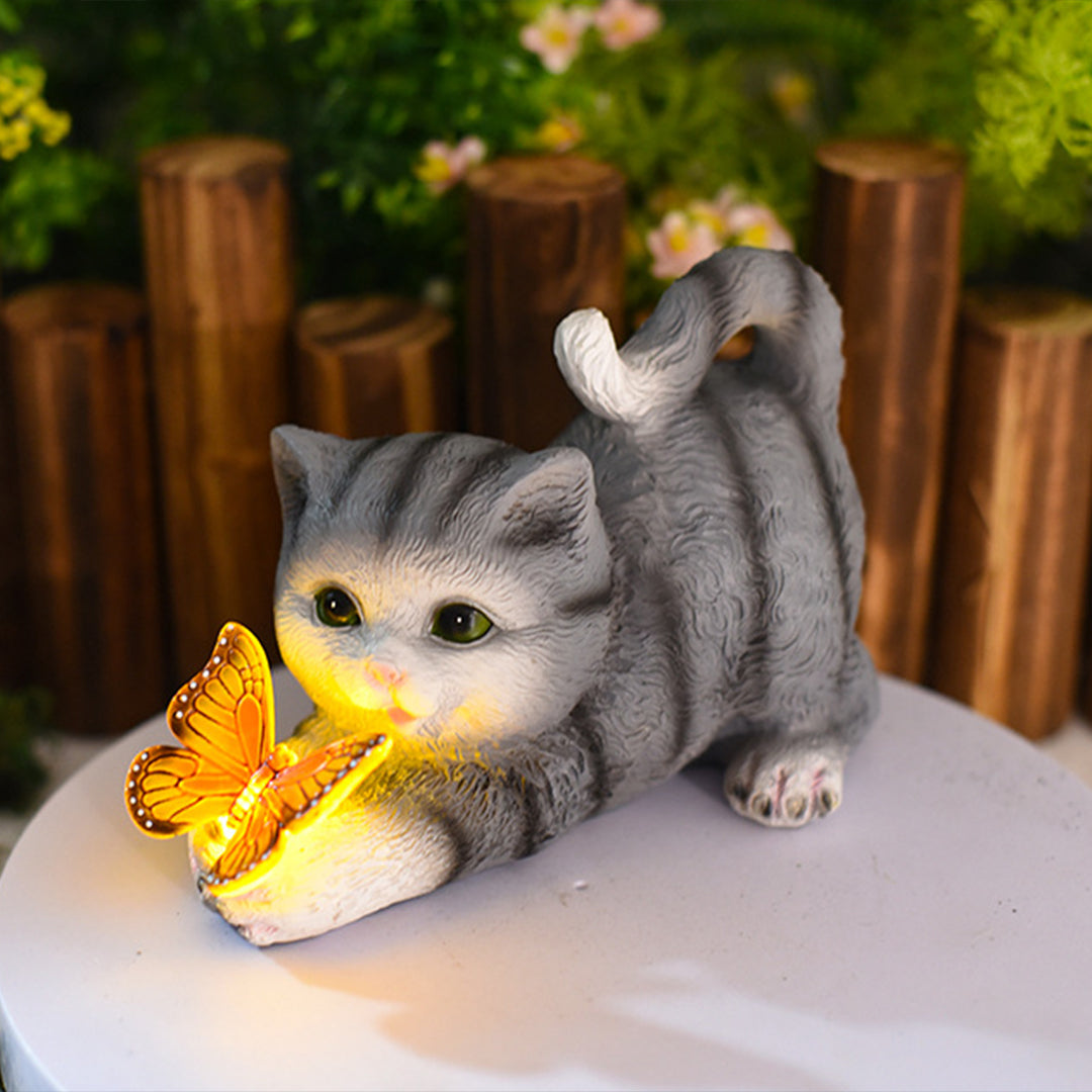 Tabby kitten figurine with luminous butterfly positioned on outdoor table setting