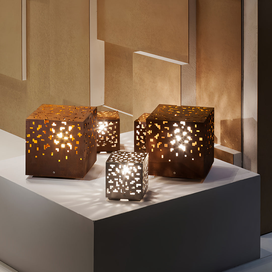 Black outdoor lantern lights displayed on a tabletop, projecting artistic light patterns onto surrounding walls.