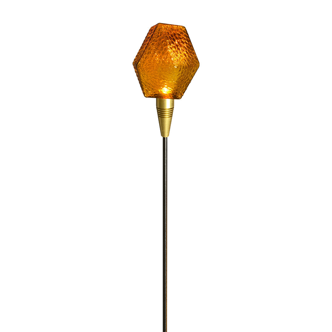 Tall amber globe stake light with minimalist black rod, glowing warmly as landscape lighting pathway decor.