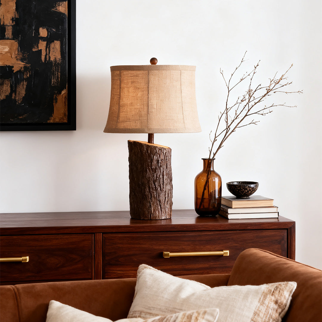 Tall accent faux wood table lamp providing ambient light on a dark dresser, complementing the nature-themed decor.